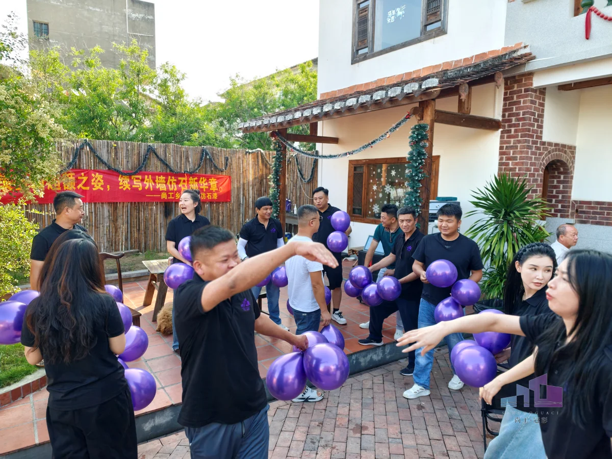 福建尚工乡墅装饰工程有限公司团队活动，全员在“尚工乡墅高端仿石漆”横幅前的别墅庭院内欢聚互动。