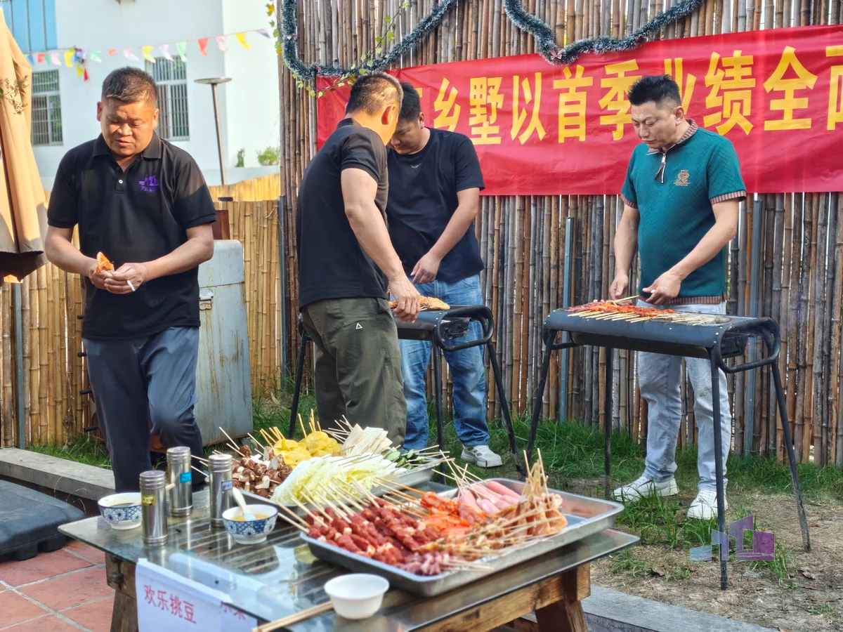 福建尚工乡墅装饰工程有限公司团队活动现场，多位员工在户外营地烤炉前并肩协作、烹饪团建烧烤美食。