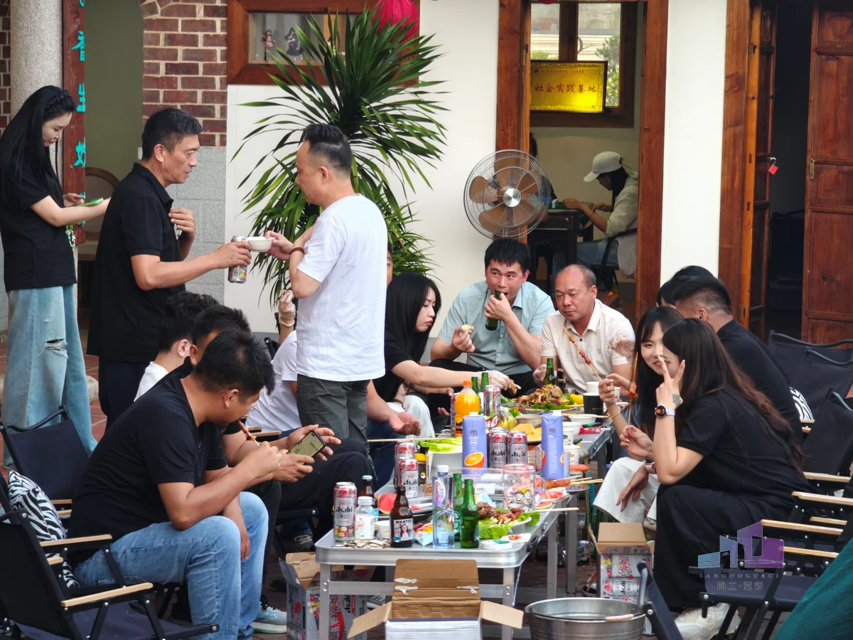 福建尚工乡墅装饰工程有限公司团队活动剪影，全体员工在户外庭院聚餐中举杯畅饮、热闹欢聚。