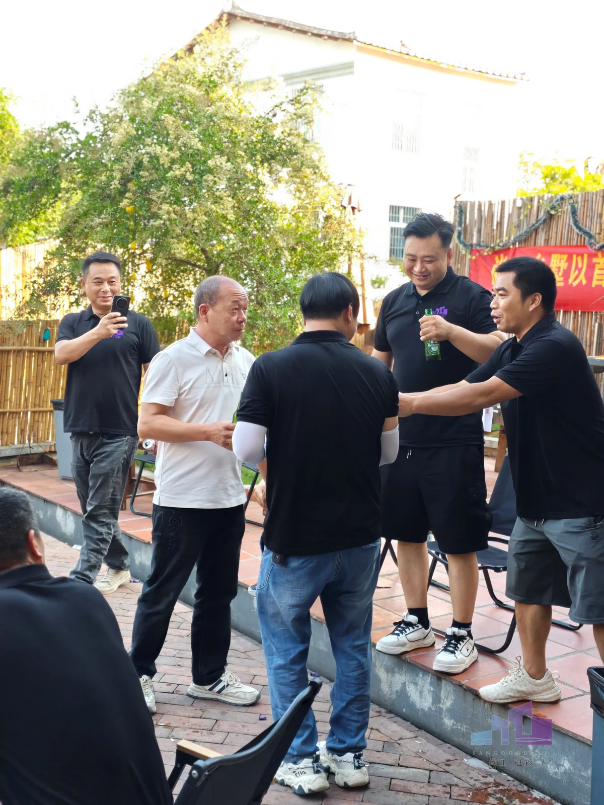 福建尚工乡墅装饰工程有限公司团队拓展活动，员工们在户外庭院聚餐时轻松碰杯、热闹互动，展现和谐的企业文化。